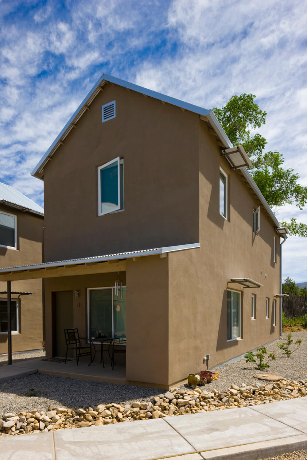 A two-story detached house at Taos Haus in Taos, New Mexico, with a covered entry and a small table and chairs