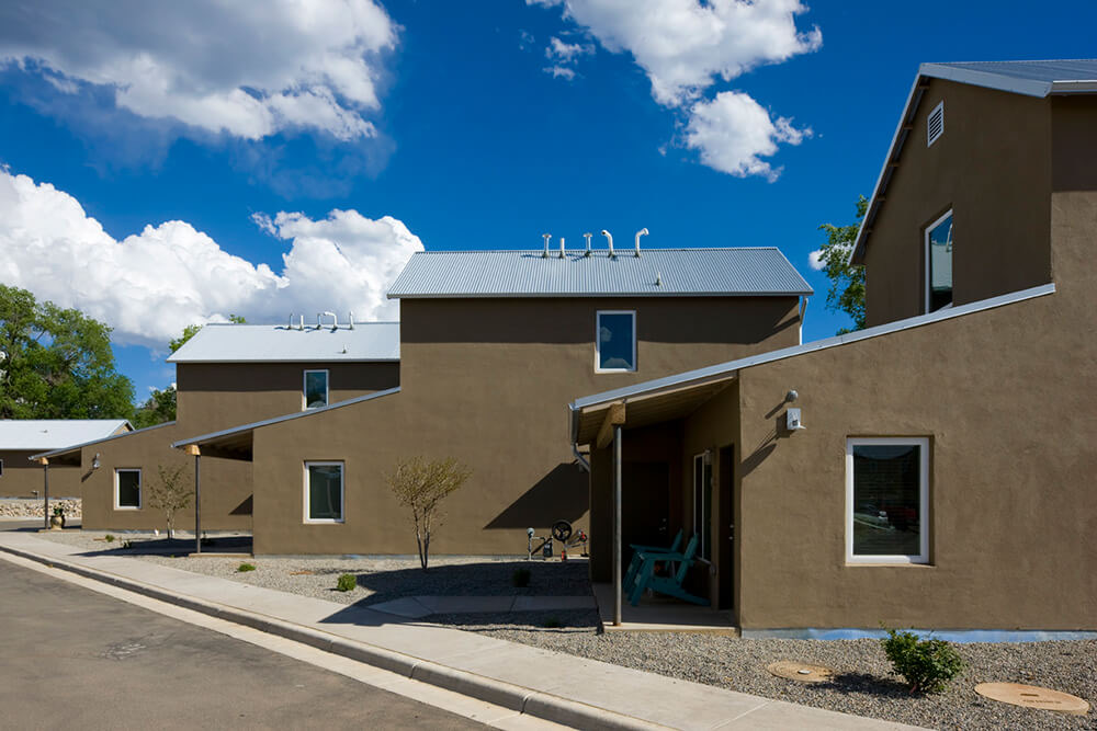 Street view of detached houses at Taos Haus with young trees and gravel landscaping