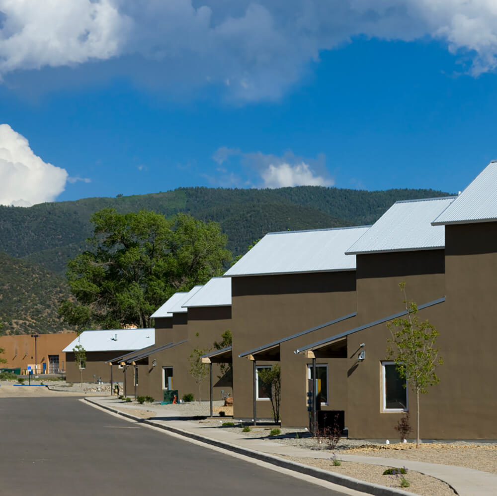 Detached houses at Taos Haus with forested mountains rising directly behind them