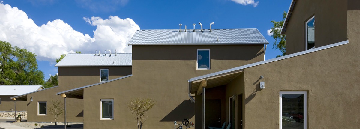 Panoramic view of the two-story stucco houses at Taos Haus under a bright New Mexico sky